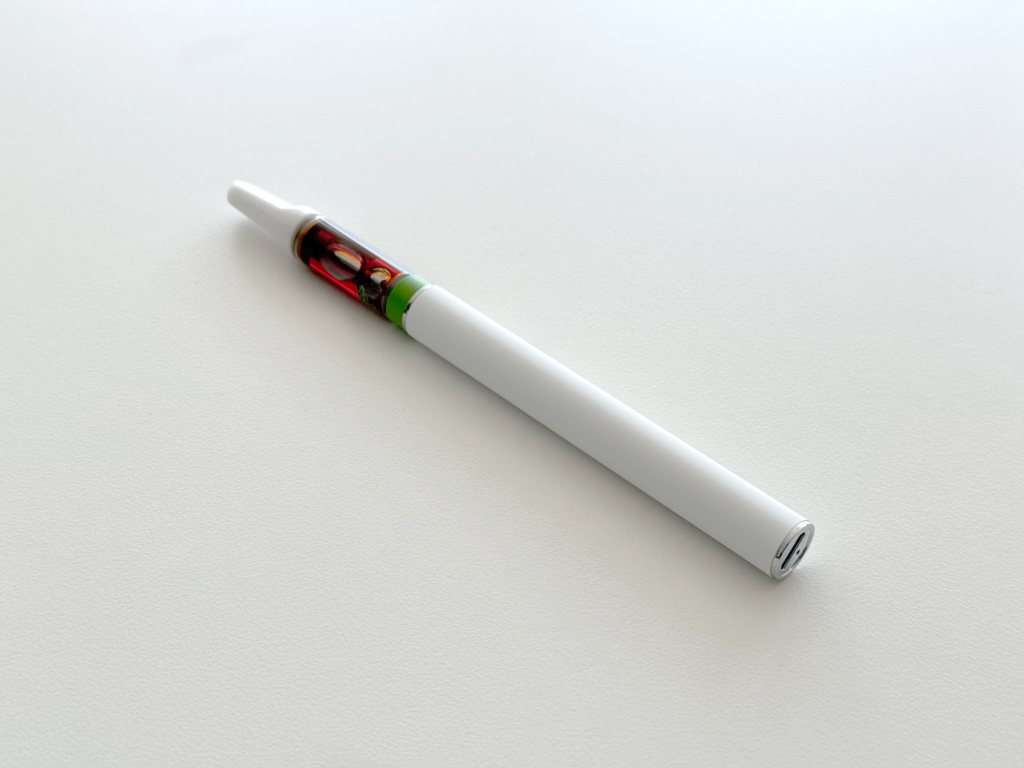 THC vape cartridge and white battery on a white table